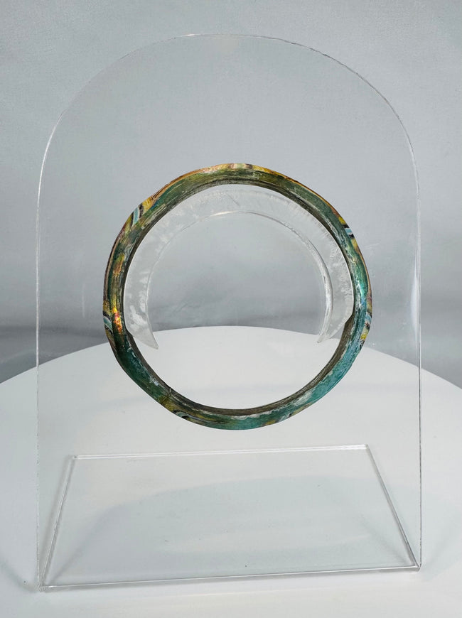 Ancient Roman polychrome glass bracelet displaying intricate striped decoration and archaeological iridescence.