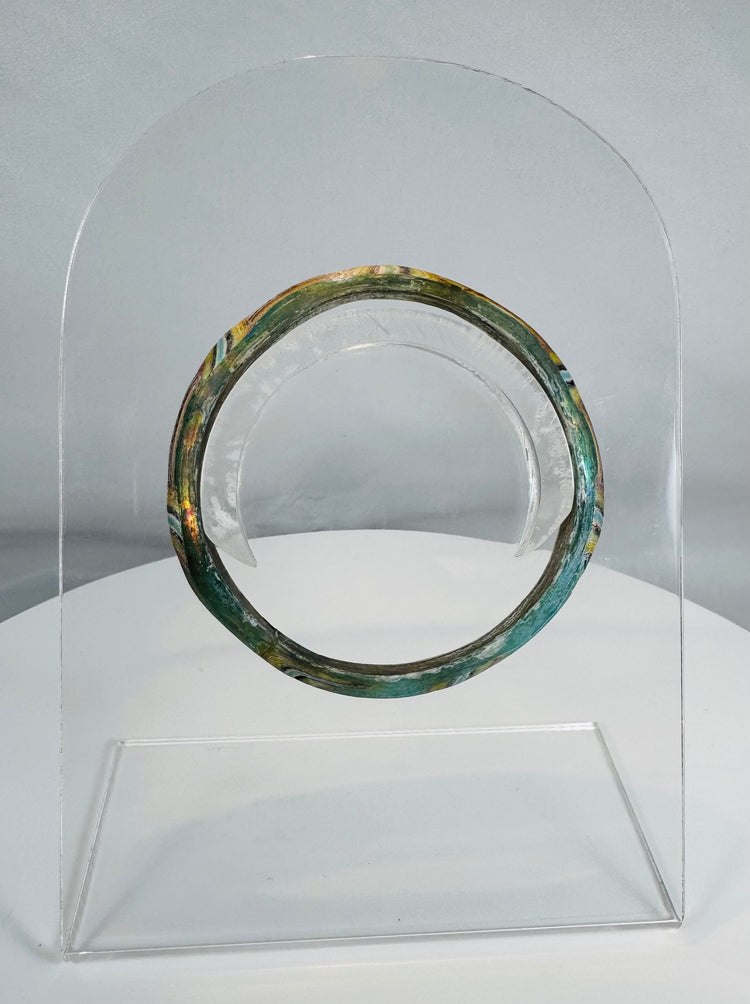 Ancient Roman polychrome glass bracelet displaying intricate striped decoration and archaeological iridescence.