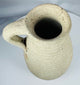 Side profile of an Ancient Roman terracotta pitcher showing the loop handle, neck, and rounded body.