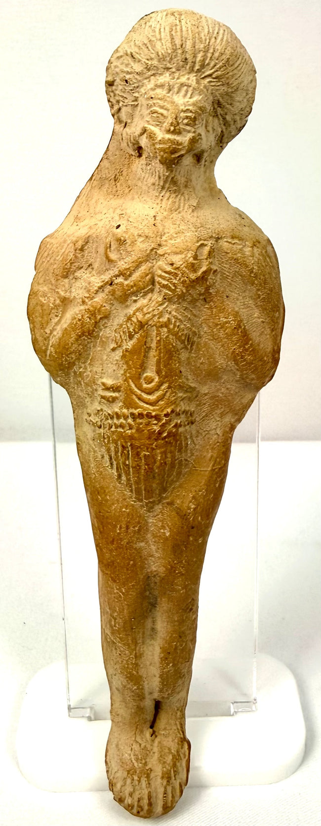 Frontal shot of antique terracotta statue displaying smiling bearded face and wide hips