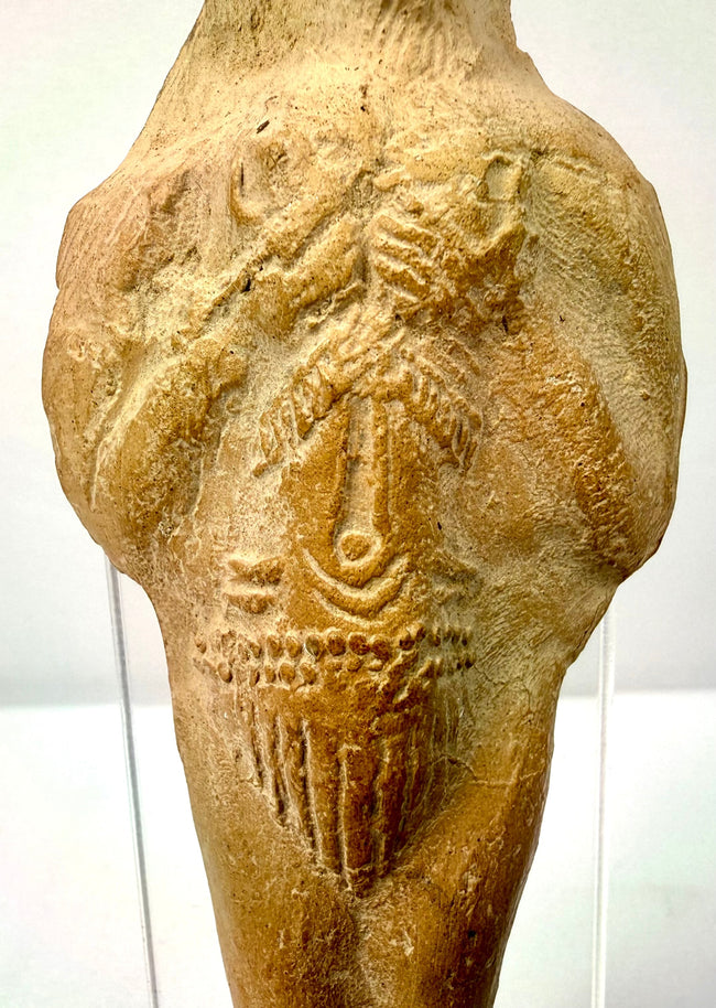 Detail of rough hand-formed terracotta texture with carved arm lines and central symbol