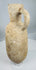 Ancient Mediterranean terracotta pouring jar displaying coarse buff-colored clay and natural mineral deposits.
