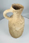 Ancient terracotta ceramic pouring vessel from the Mediterranean featuring a flared rim and rounded base.