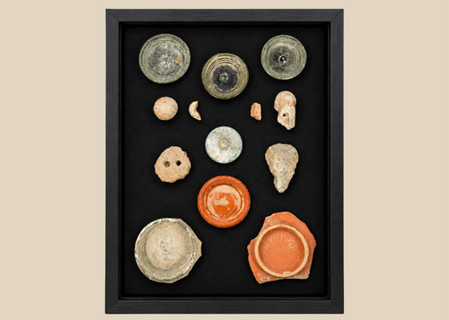 Comparative archaeological shadow-box showing ancient glass, ceramics, and stone artifacts