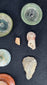 Worked grey stone implement displayed with Roman and Near Eastern archaeological fragments