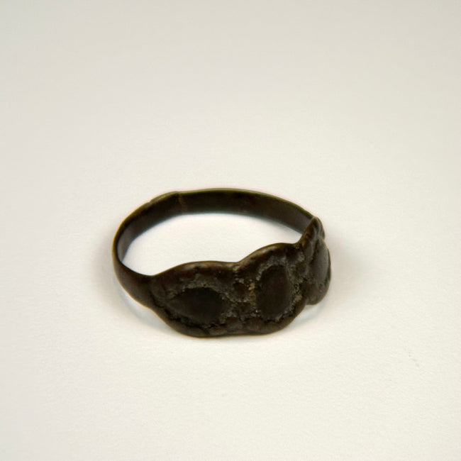 Ancient silver jewelry with three connected oval forms and visible age-related surface wear