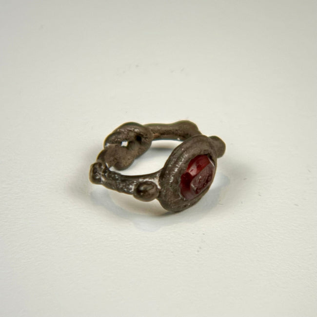 Ancient garnet intaglio signet ring with decorative silver shoulders and preserved dark red gemstone