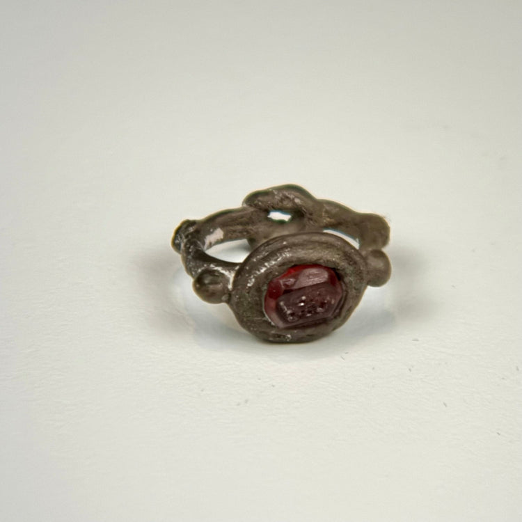 Late Roman to Early Byzantine silver ring displaying the engraved garnet intaglio, aged patina, and ornamental bezel design
