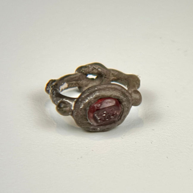 Ancient silver signet ring featuring an engraved red garnet intaglio and ornamental side nodes