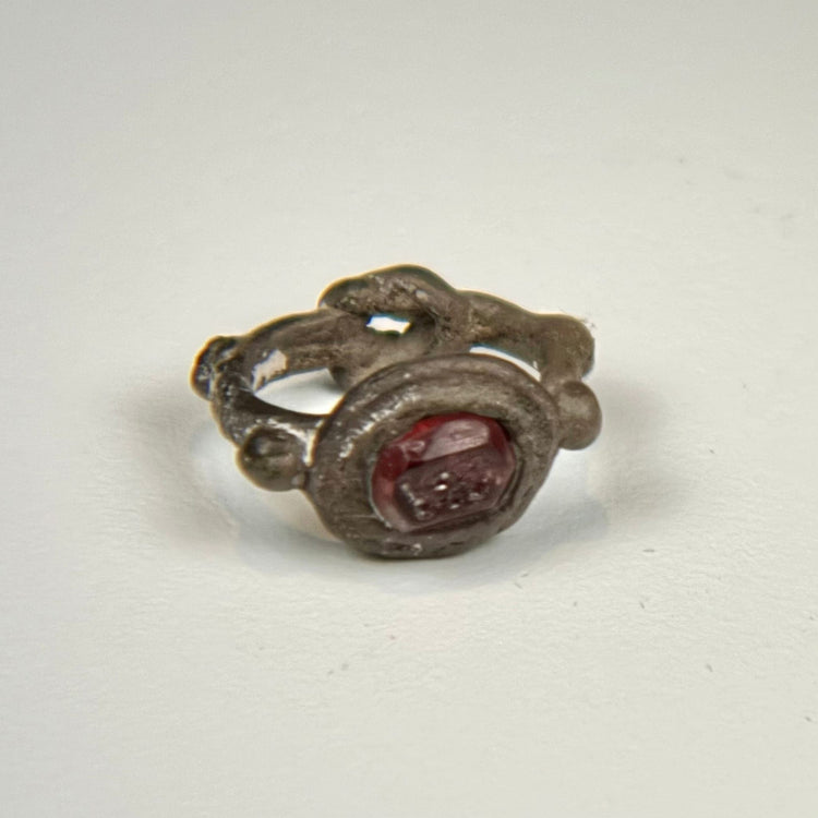 Ancient silver signet ring featuring an engraved red garnet intaglio and ornamental side nodes