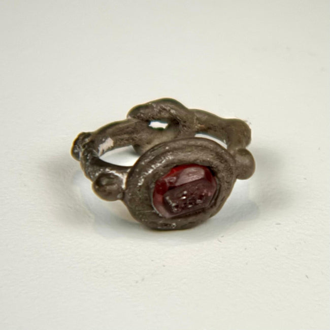 Late Roman silver ring with deep red garnet intaglio and decorative raised bezel, circa 300–600 CE