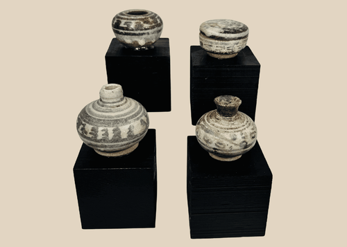 Group of four miniature Sawankhalok glazed stoneware vessels from Thailand's Sukhothai Period, featuring underglaze painted decoration and custom display stands.