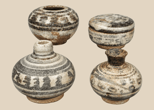 Group of four miniature Sawankhalok glazed stoneware vessels from Thailand's Sukhothai Period, featuring underglaze painted decoration and custom display stands.