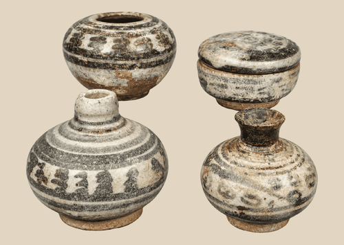 Group of four miniature Sawankhalok glazed stoneware vessels from Thailand's Sukhothai Period, featuring underglaze painted decoration and custom display stands.