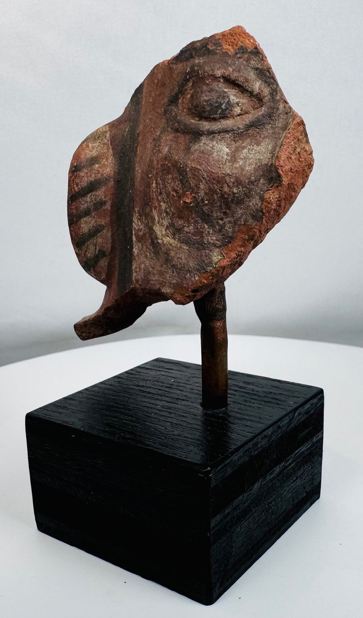 Ancient Americas ceramic fragment depicting a stylized human face with large ear ornament