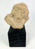 Terracotta fragment of a stylized anthropomorphic figure with almond-shaped eyes, prominent nose, and incised chest details, mounted on a modern wood base; likely from West Mexico (Nayarit or Jalisco) or Iberian/Roman provincial context, circa 200 BCE–2nd Century CE.