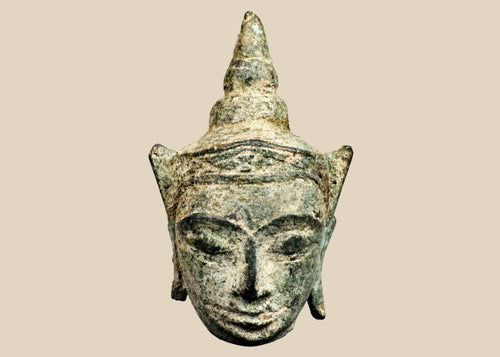 Small antique Southeast Asian bronze Buddha head, likely from Thailand or Cambodia, 16th–17th Century CE. Features serene expression, elongated earlobes, pointed ushnisha, and natural green patina. Originally part of a larger statue, serving as a devotional object reflecting Buddhist spiritual symbolism, artistry, and enlightenment.