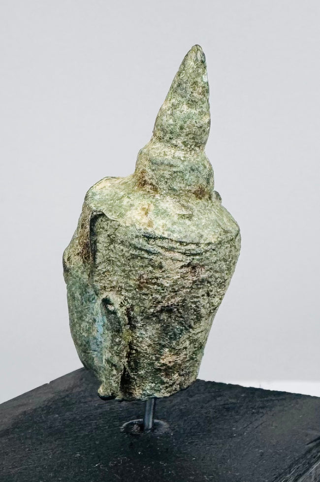 Historic bronze Buddha head with peaceful facial features, elongated ears, and centuries-old verdigris patina