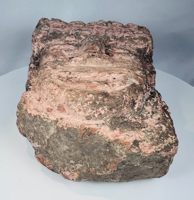 Weathered Mesoamerican stone carving with archaeological deposits