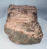 Weathered Mesoamerican stone carving with archaeological deposits