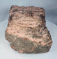 Weathered Mesoamerican stone carving with archaeological deposits