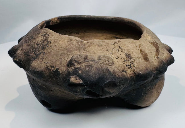 Close-up of the modeled zoomorphic heads decorating the rim of an authentic Pre-Columbian terracotta tripod vessel.
