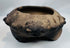 Close-up of the modeled zoomorphic heads decorating the rim of an authentic Pre-Columbian terracotta tripod vessel.