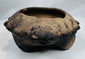 Close-up of the modeled zoomorphic heads decorating the rim of an authentic Pre-Columbian terracotta tripod vessel.