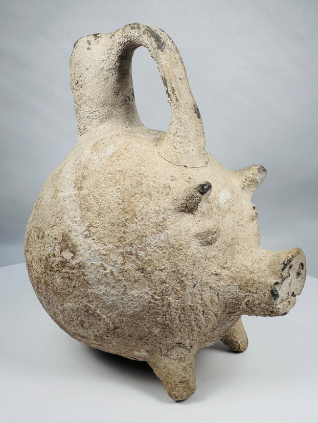 Early Bronze Age Anatolian terracotta zoomorphic pig vessel with tripod legs and arched stirrup handle.