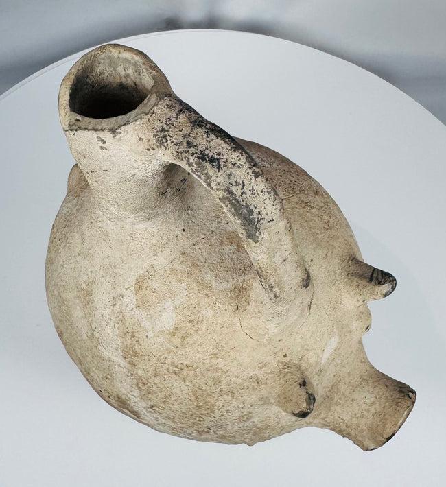 Side profile of an Early Bronze Age Anatolian terracotta pig vessel highlighting the tripod support legs.