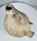 Side profile of an Early Bronze Age Anatolian terracotta pig vessel highlighting the tripod support legs.