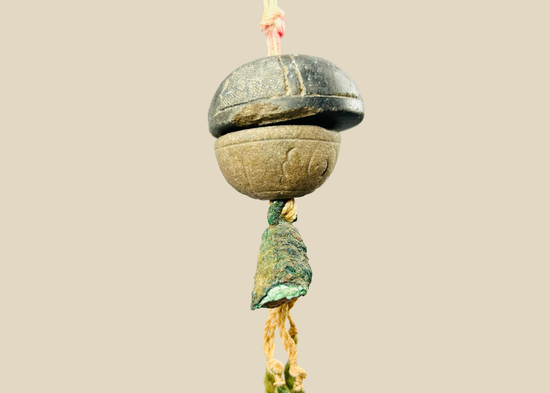 Ancient bronze bell pendant suspended on original fiber cord — full front view showing patina and form