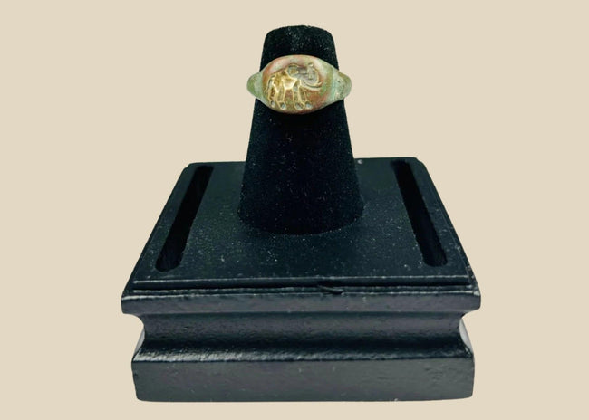 Ancient bronze ring with a finely engraved elephant motif on the bezel, green patina from age, symbolizing wisdom, power, and protection, circa 1st Millennium BCE.