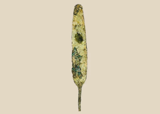 Ancient bronze spearhead from the Early to Late Bronze Age (circa 3300–1200 BCE). Leaf-shaped blade with tapered point, mounted on a modern display base. Exhibits natural patina and surface oxidation, reflecting early metallurgical craftsmanship and use in hunting or combat.