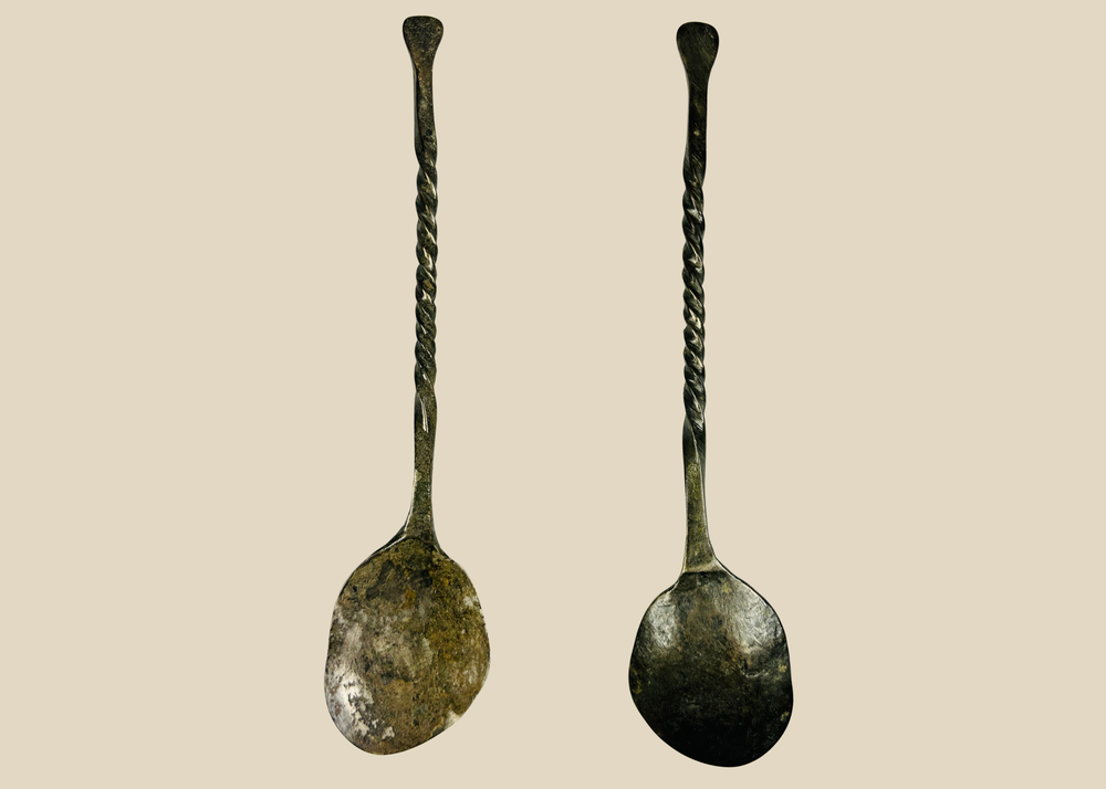 Front view and back view of single ancient bronze spoon showing twisted handle and shallow oval bowl.