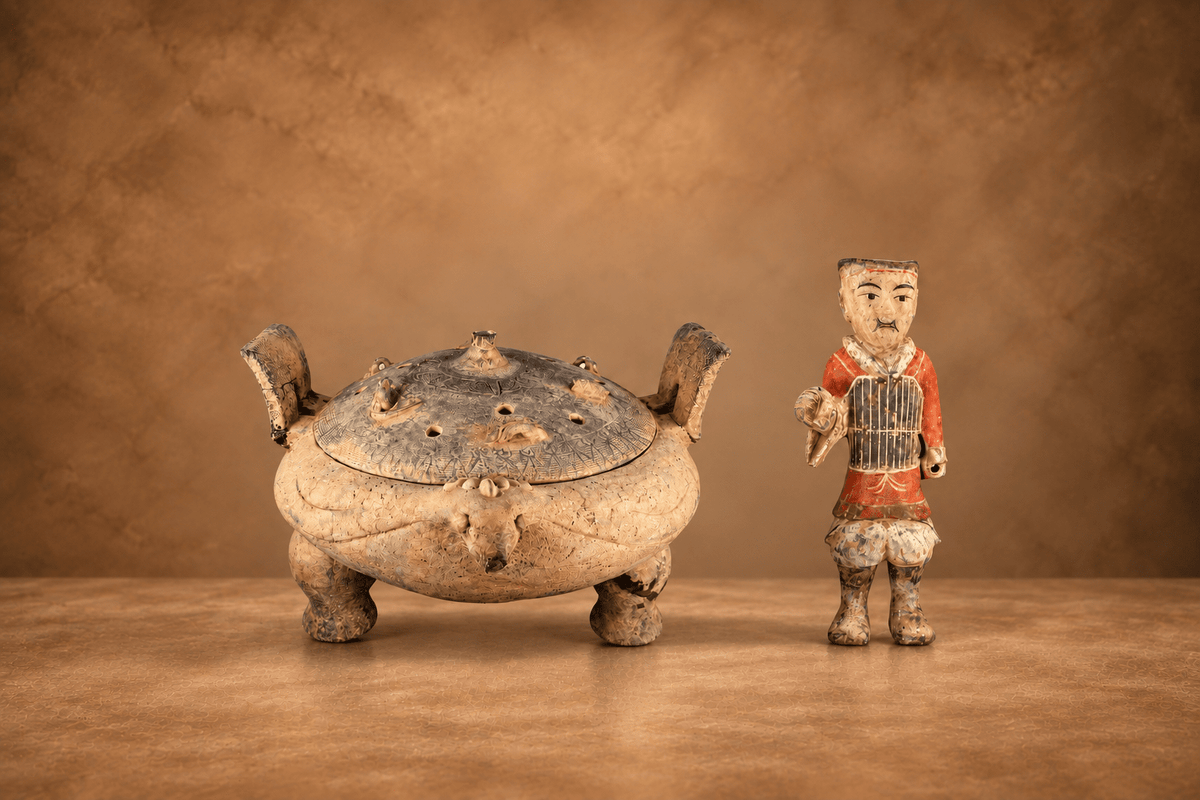 Ancient ceramic censer with fitted lid displayed beside a painted attendant figurine on a warm brown museum-style background.
