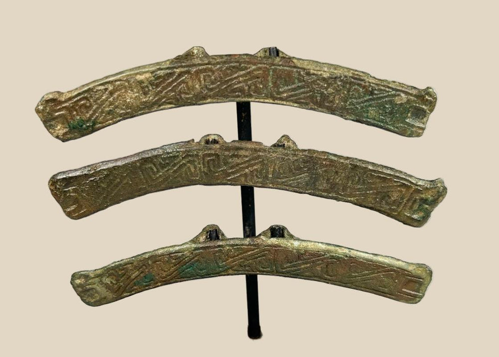 Ancient Chinese bronze chariot fittings, 475 BCE–220 CE, with curved form, rear hooks, engraved inscriptions, and rich green patina on custom stands.