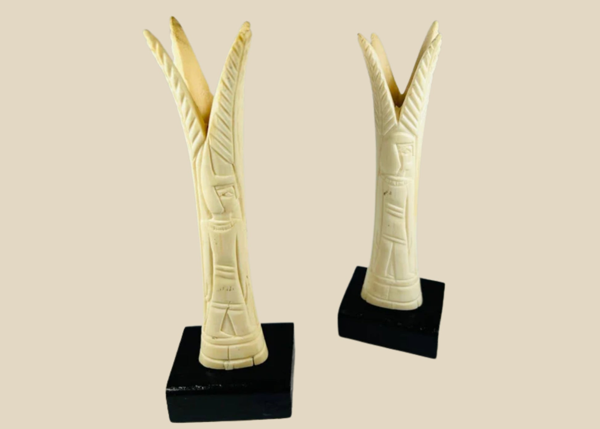 Pair of carved Egyptian ivory sistrum handles on black display bases, featuring stylized figures and decorative motifs, dating to the Third Intermediate Period, circa 1070–664 BCE.