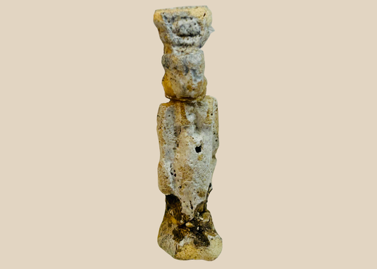 Ancient Egyptian faience amulet figure with heavy burial patina shown upright.