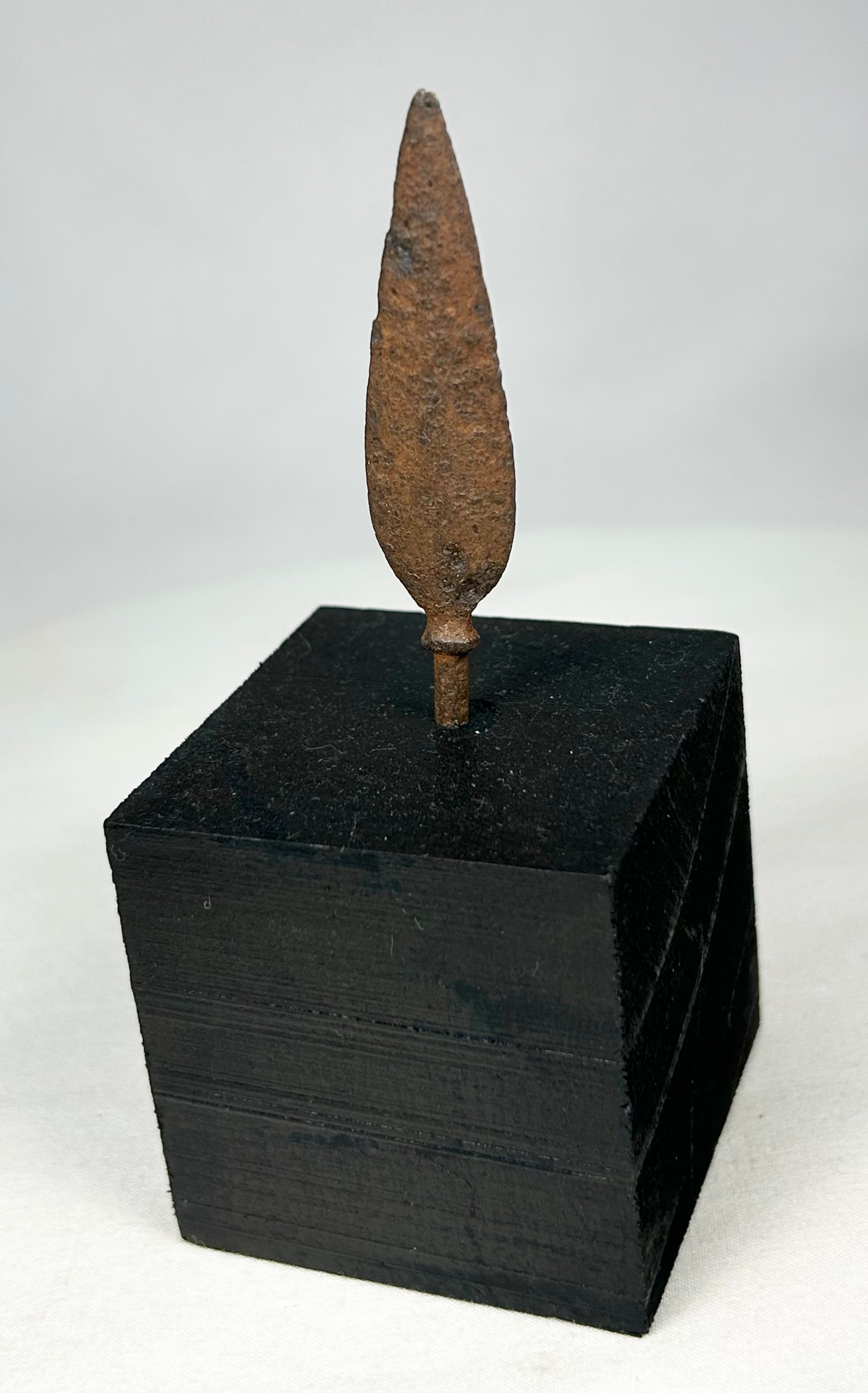 Ancient European iron arrowhead relic mounted on black display base, front view