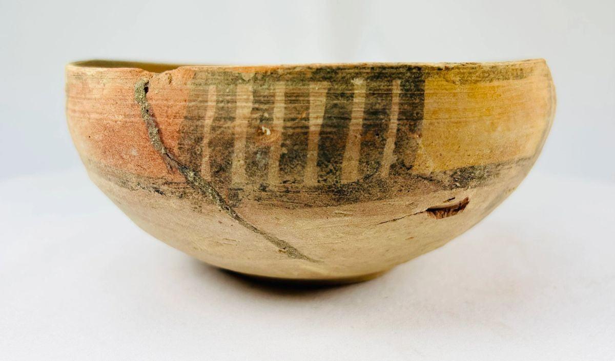 Two ancient Indus Valley terracotta bowls, circa 2nd–3rd millennium BCE; one plain with natural earthen patina, the other decorated with geometric polychrome painted motifs, both exhibiting age wear and archaeological restoration.