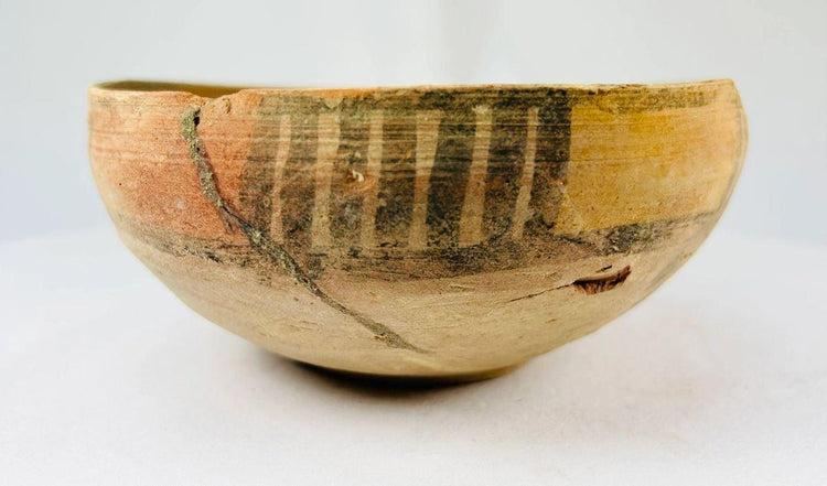 Two ancient Indus Valley terracotta bowls, circa 2nd–3rd millennium BCE; one plain with natural earthen patina, the other decorated with geometric polychrome painted motifs, both exhibiting age wear and archaeological restoration.
