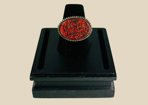 Oval carnelian intaglio ring from the Ancient Near East, 1st millennium BCE. Features engraved animal and symbolic motifs on red carnelian, set in a silver bezel, displayed on a black stand. Excellent condition with finely detailed intaglio carvings.