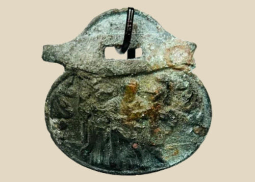 Ancient Roman bronze pendant, 1st–4th century CE, engraved with three standing figures including a helmeted figure, green patina, mounted on a custom stand.