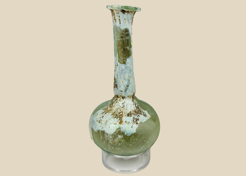 Ancient Roman glass bottle with rounded body and long flared neck, pale green hue and iridescent patina.