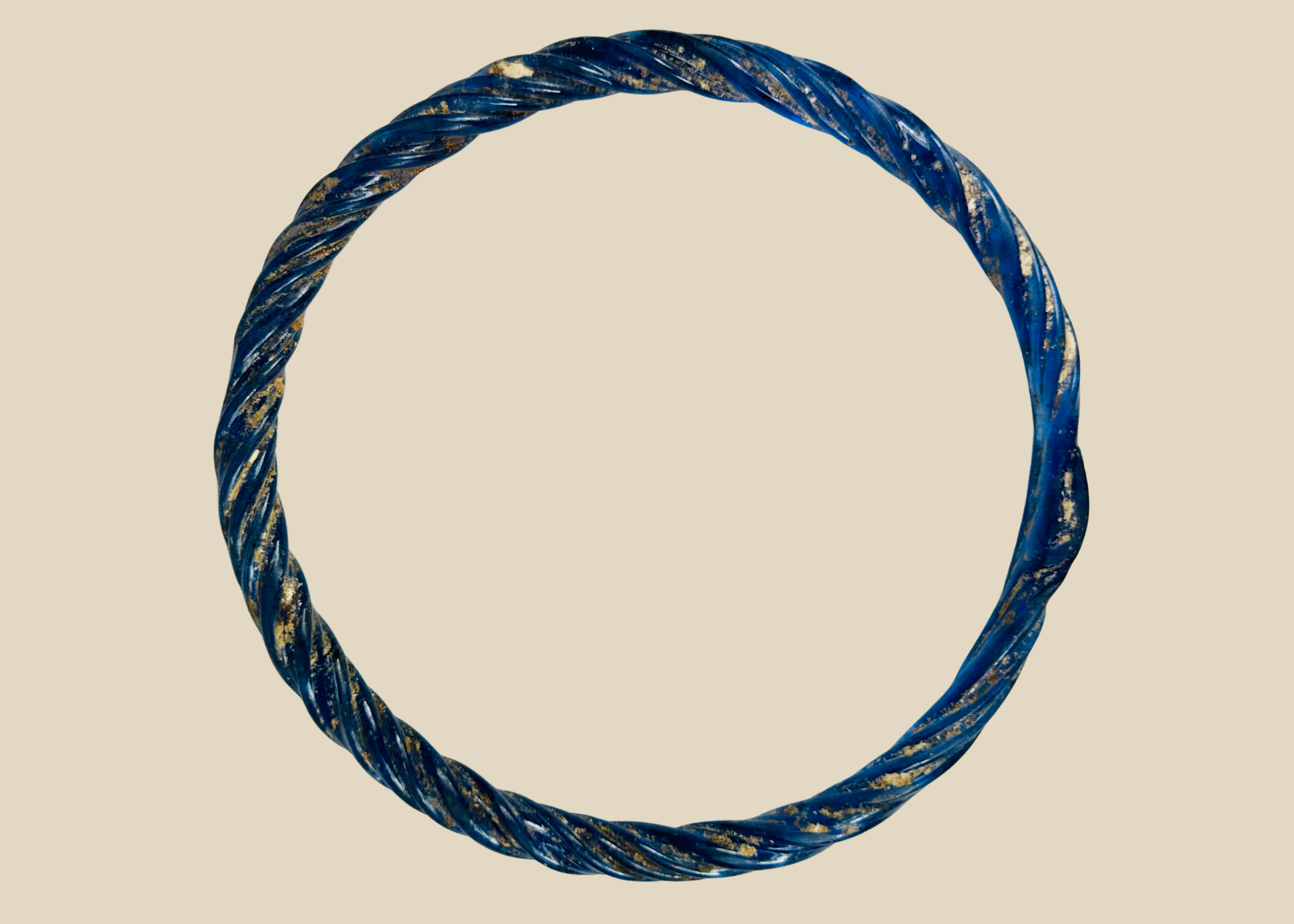 Ancient Roman glass bracelet with cobalt-blue hue, twisted design, and iridescent patina from antiquity.