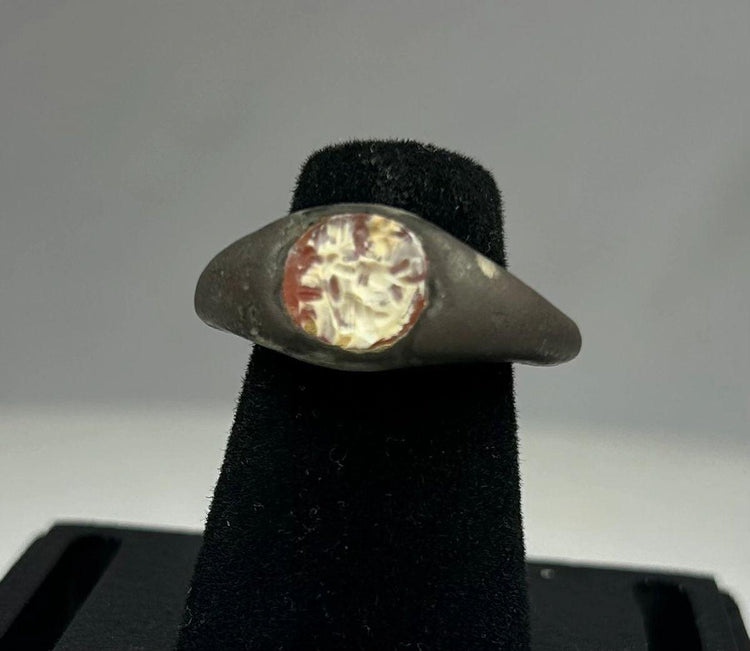 Ancient silver ring from the Mediterranean or Near East, 1st Millennium BCE, featuring a polished carnelian intaglio with traces of engraved motif. Smooth silver band with natural patina highlights the gemstone, reflecting its use as both a personal adornment and protective talisman in antiquity.
