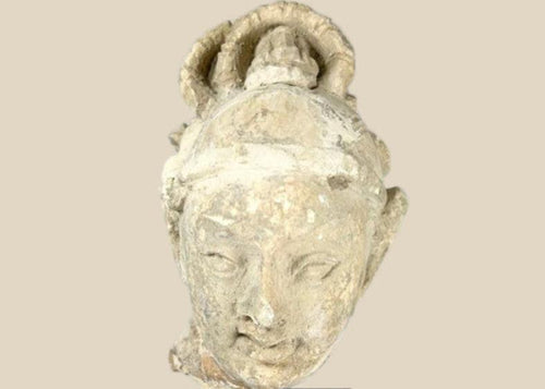 Stucco Buddha head fragment on black display base, featuring serene facial expression, stylized hair, and partial halo, likely from Southeast Asia, 12th–13th century CE.