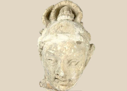 Stucco Buddha head fragment on black display base, featuring serene facial expression, stylized hair, and partial halo, likely from Southeast Asia, 12th–13th century CE.