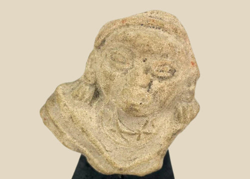 Terracotta fragment of a stylized anthropomorphic figure with almond-shaped eyes, prominent nose, and incised chest details, mounted on a modern wood base; likely from West Mexico (Nayarit or Jalisco) or Iberian/Roman provincial context, circa 200 BCE–2nd Century CE.
